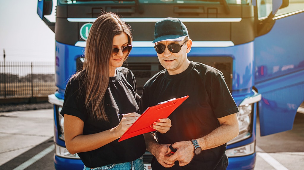 Young semi truck driver reviews paperwork with her mentor.